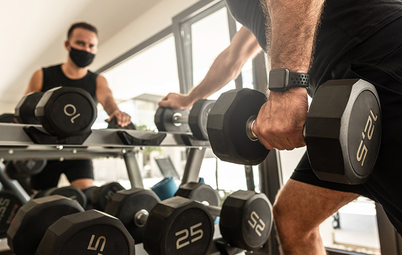 Young athletic man wearing a prevention face mask during his workout in the gym
