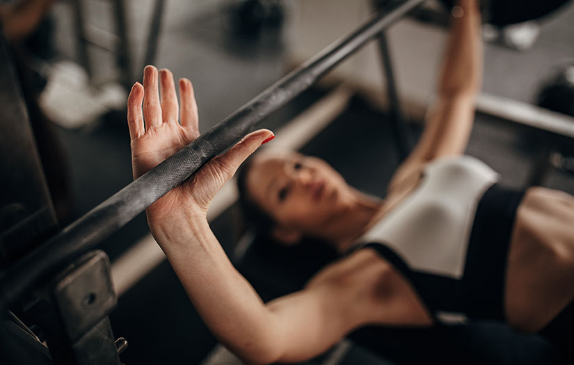 Fit woman doing bench press exercise in gym
