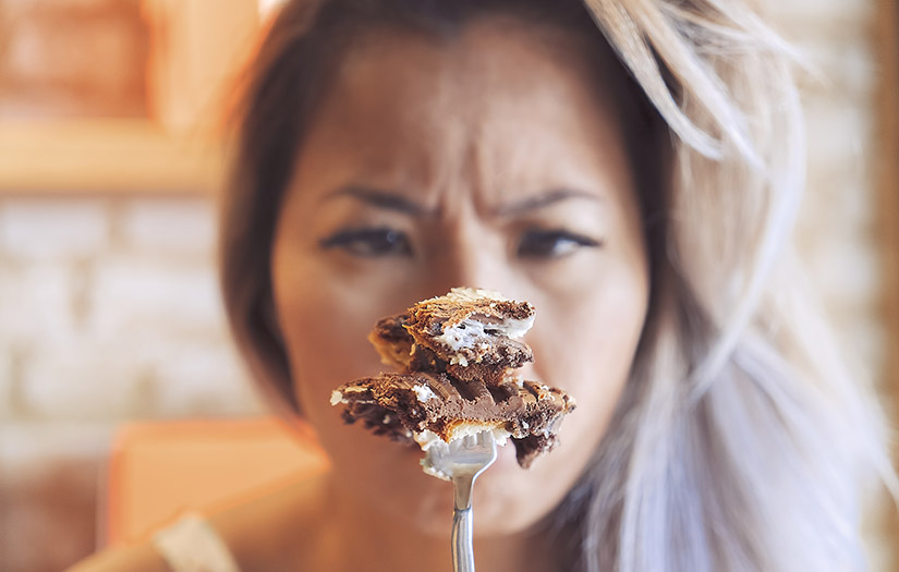 Depressed and angry woman comforting herself, eating cake